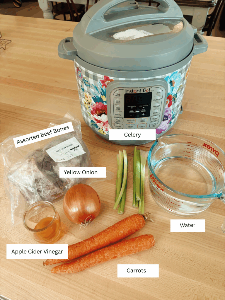 The ingredients needed for the beef bone broth laid out on a wood butcher block. Includes: celery, water, carrots, yellow onion, assorted beed bones, apple cider vinegar, and an instant pot.