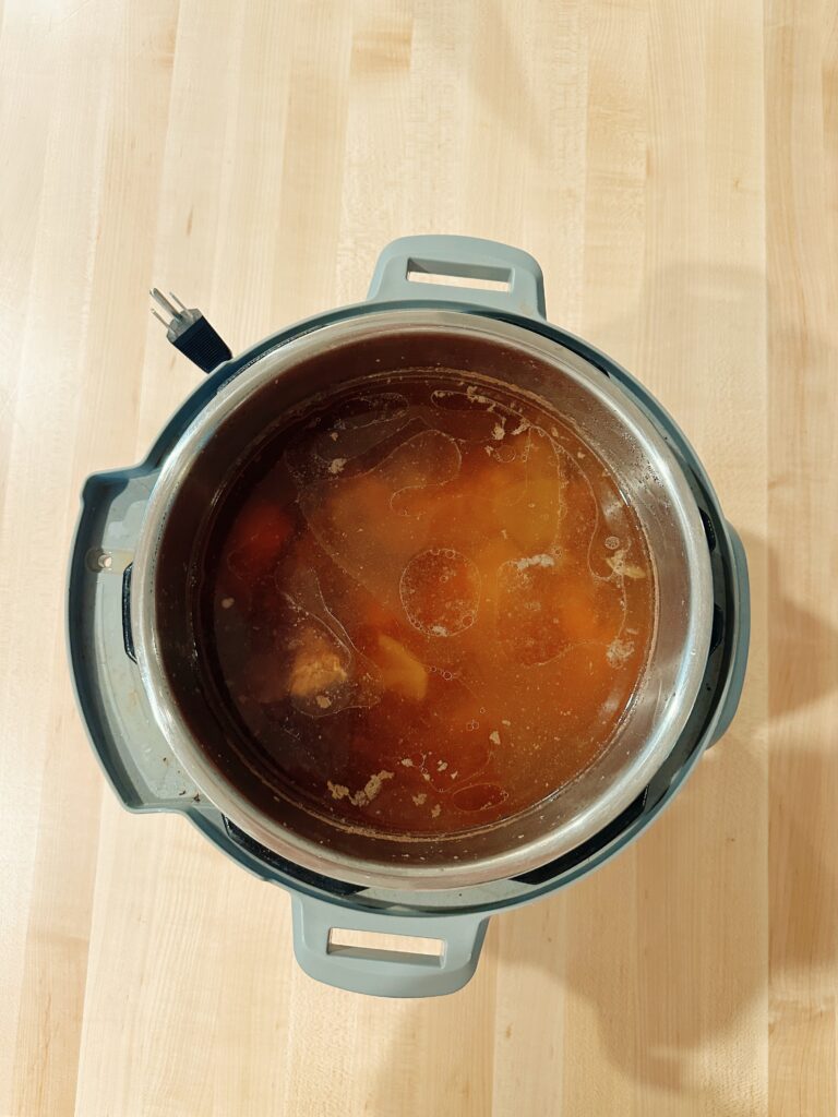 The open instant pot is showing the now cooked bone broth that is still hot.
