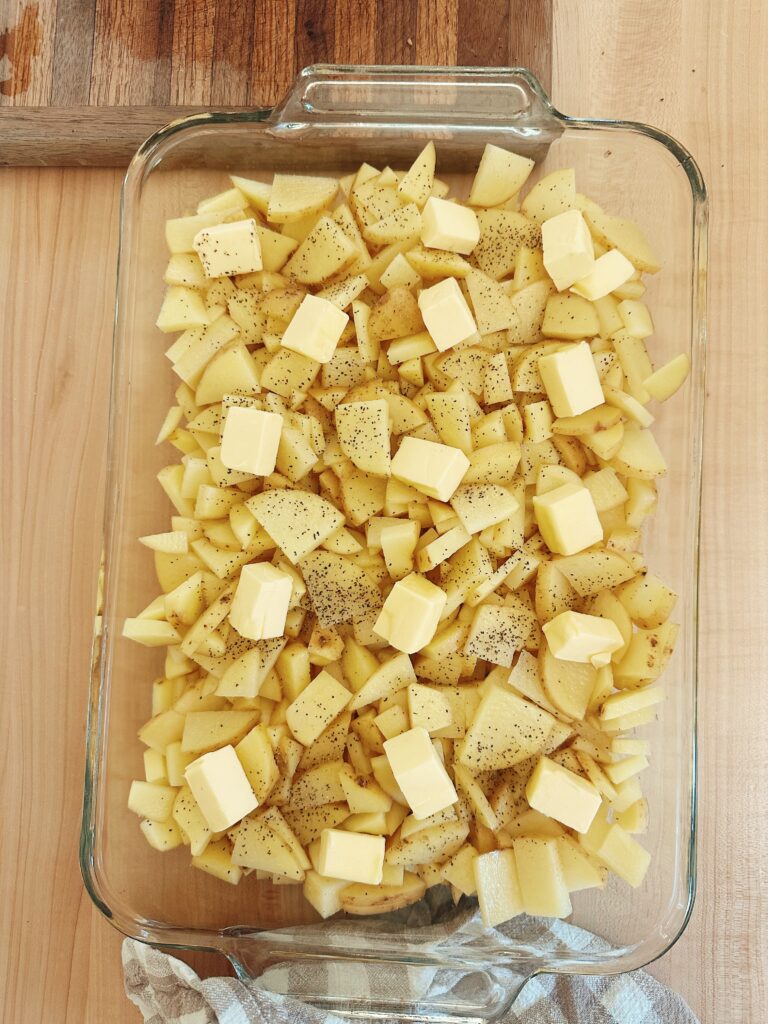 The butter chunks are now places on top of the seasoned potato slices.
