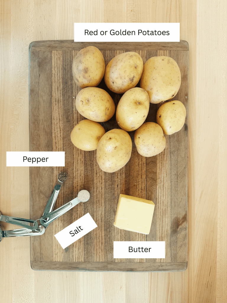 Ingredients that are included in this recipe. Nine golden potatoes, a teaspoon salt and pepper, and a block of butter. All on top of a wood cutting board.