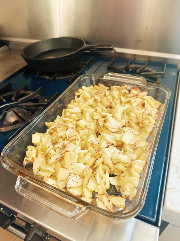 The combination of potatoes, butter, and seasoning have been partially baked in the oven and are brown and crispy on top.