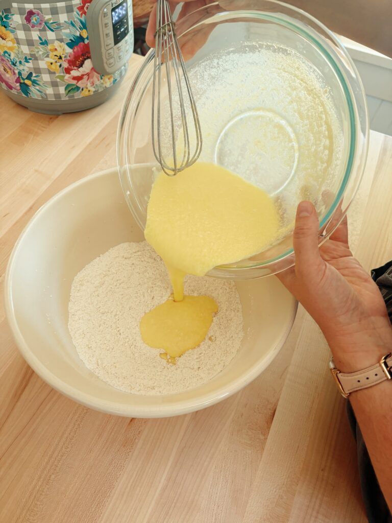 Pouring the liquid ingredients into the glass bowl with the dry ingredients. 