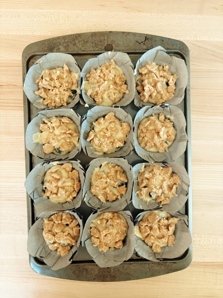 A photo of all 12 of the unbaked muffins covered with the crumble. 