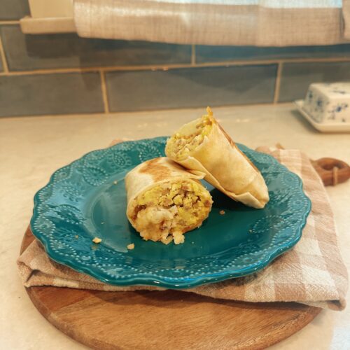 Sausage, Egg, and Cheese Breakfast Burrito laid neatly on a teal glass plate.