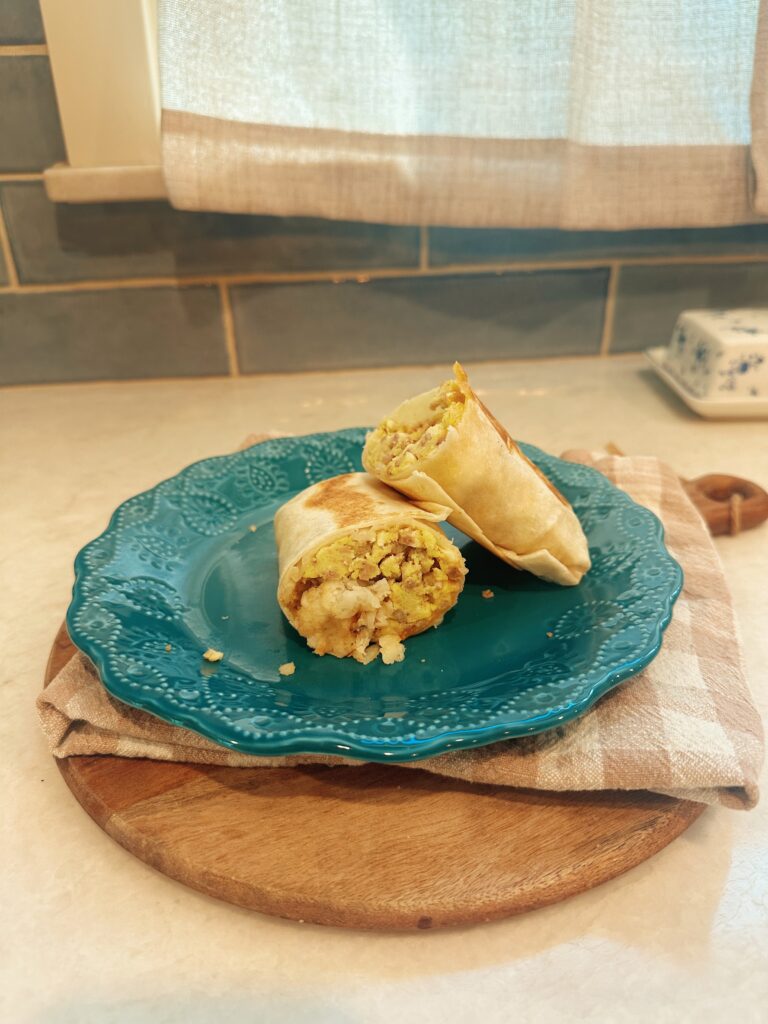 Sausage, Egg, and Cheese Breakfast Burrito laid neatly on a teal glass plate.